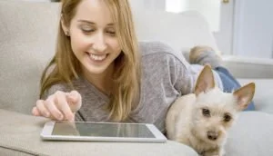 Tablet para juegos: Mejores tablets para jugar actuales. Chica juega con tablet junto a perro.