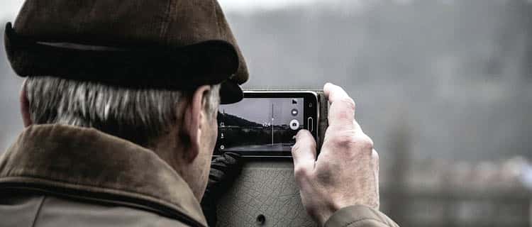 Hombre mayor toma fotos con el móvil. Móviles para regalar a personas mayores